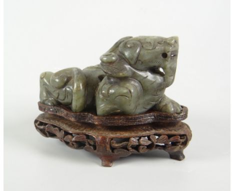 CHINESE SPINACH JADE STUDY OF A RECUMBENT LION DOG raised on carved hardwood base, 8cms high Condition Report: surface wear a