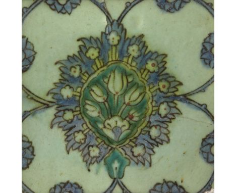 A Damascus Iznik tile, 17th century, of square form, part of a repeating design, painted under the greenish glaze in green an