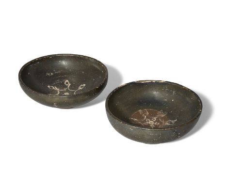 Two black glazed pottery bowls, each on a raised ring base, the tondo decorated with impressed decoration, on the first with 