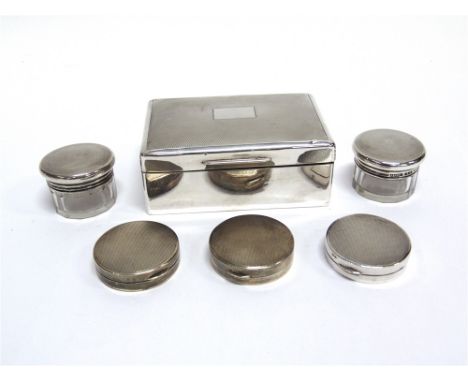 A SILVER CIGARETTE BOX a pair of glass toilet jars with silver covers; and three silver circular boxes; all with engine turne