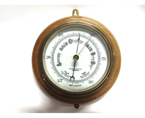 AN ANEROID BAROMETER  with a brass case, retailed by John Barker & Co. Ltd of Kensington, set to a circular oak plaque, overa