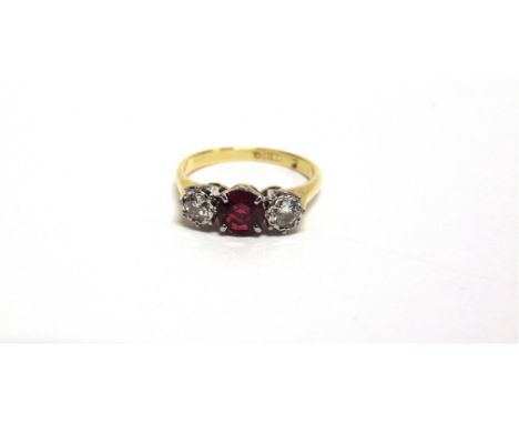 A SYNTHETIC RUBY AND DIAMOND THREE STONE RING stamped '18ct', the two brilliant cuts totalling approximately 0.24 carats, fin