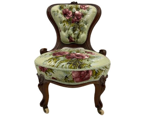 Victorian walnut framed nursing chair, spade shaped back carved with flower heads, upholstered in buttoned rose patterned fab