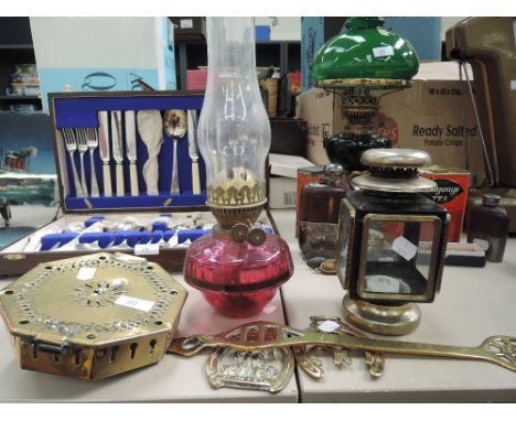 A selection of brass wares and lamps including cranberry glass well oil lamp and chestnut roaster