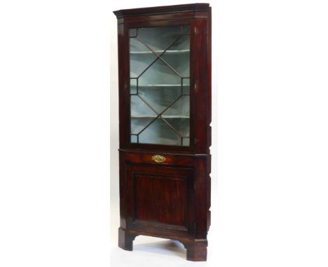 An early 19thC mahogany standing corner cabinet, with a moulded cornice above an astragal glazed door enclosing shaped shelve