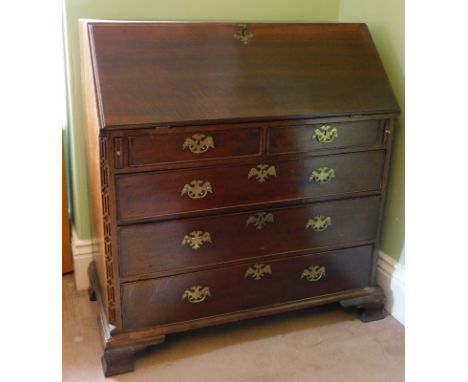 A George III oak bureau, with fall flap revealing a fitted interior, resting on lopers, three short and three long graduated 