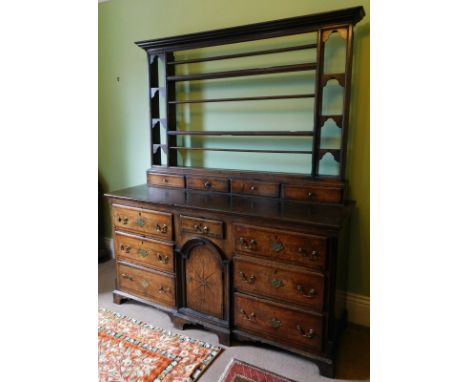 An 18thC oak dresser, with plate rack back having four long spice drawers, the base having central drawer over an arched pane