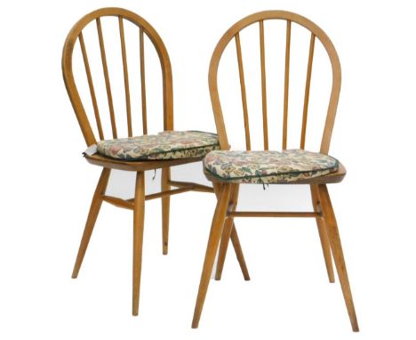 A pair of Ercol stick back kitchen chairs, each with a solid seat on turned tapering legs.