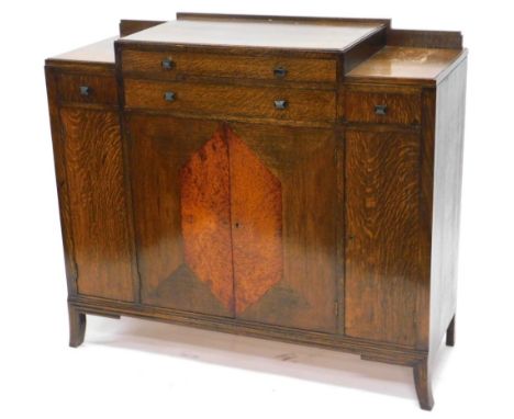 An Art Deco oak and amboyna sideboard, of stepped form with two long and two short drawers above four doors with splayed legs