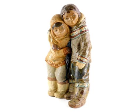 A Lladro brown ceramic figure group, modelled in the form of two embracing Eskimos, printed mark in blue to underside, 38cm h