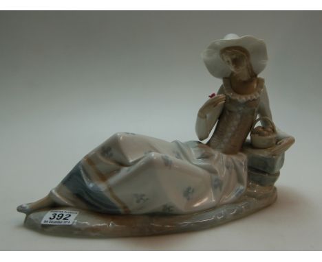 Large Nao figure of a lady reclining on a rock holding a flower, h23cm, L38cm