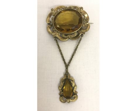 A large vintage decorative stone set drop brooch with necklace bale to rear. A large oval cut amber coloured stone in a gold 