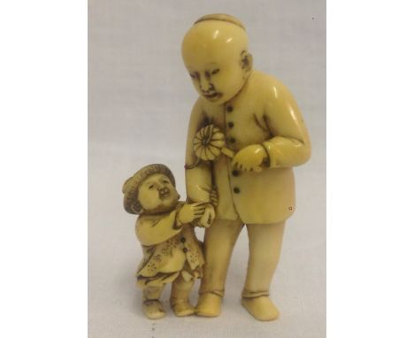 A very finely carved, 19th century Japanese ivory netsuke of a father and child, signed. The father is holding onto the child