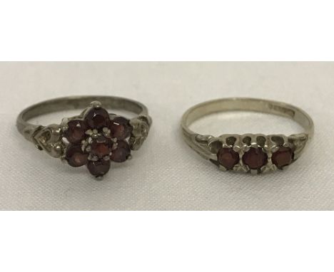 2 silver ladies dress rings both set with garnets. One ring gypsy style, set with 3 garnets, the other a flower design with s