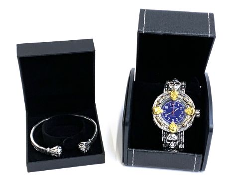 A gents wristwatch with silver tone skull design strap heightened with gold tone skulls on the bezel; together with a white m