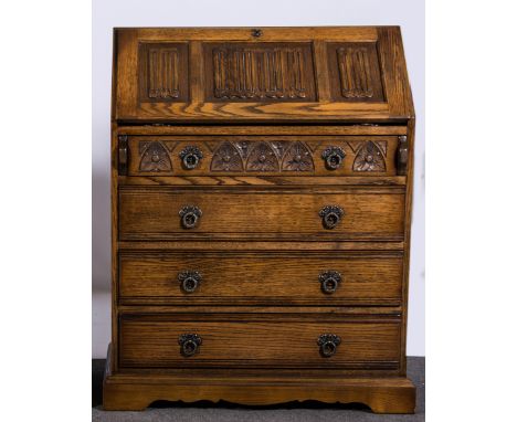 Reproduction oak  bureau, fall front with carved linen fold panel, enclosing a part fitted interior, with four long graduatin