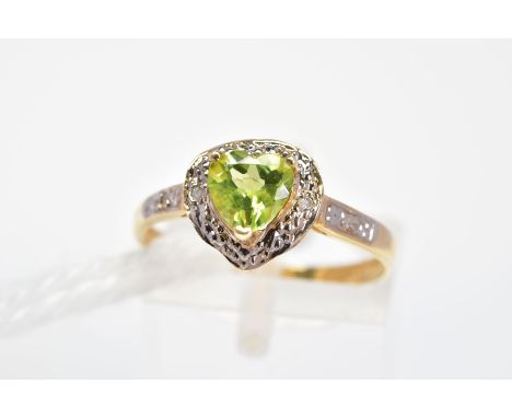 A PERIDOT AND DIAMOND DRESS RING, the heart shape peridot in a three claw setting within a surround set with two single cut d