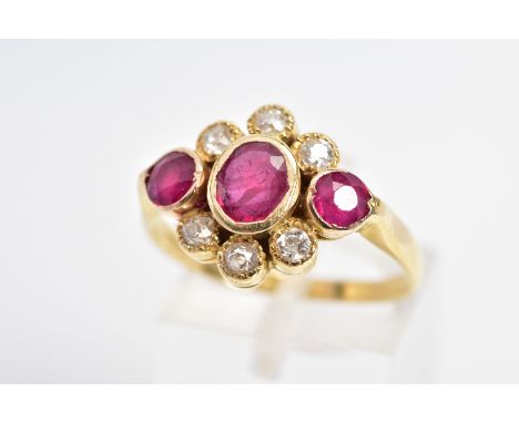 AN 18CT GOLD RUBY AND DIAMOND RING, designed as an oval ruby flanked by circular rubies, all within collet settings, within a