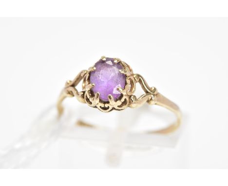 AN AMETHYST RING, the central oval amethyst within an eight claw setting to the scalloped scrolling surround and scrolling bi