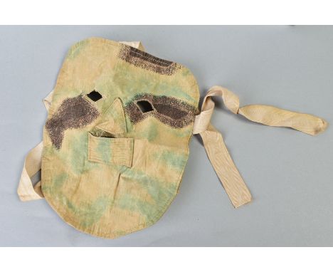 A GERMAN WWI/II ERA CANVAS/CLOTH CAMOFLOUGE SNIPER MASK, to be worn under the helmet etc, faded but complete with attachment 