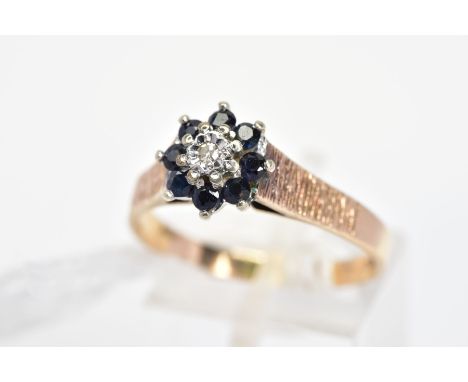 A 9CT GOLD SAPPHIRE AND DIAMOND CLUSTER RING, the central single cut diamond in an illusion setting to the circular sapphire 