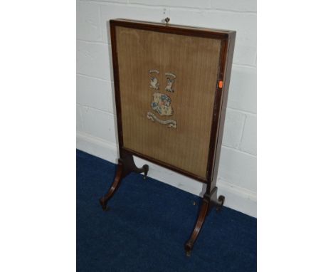 A REGENCY MAHOGANY AND EBONY INLAID FIRESCREEN with a single sliding panel and needlework coat of arms, width 56cm x height 1