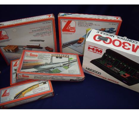 Collection of boxed Lima OO gauge railway models including crossing gates, automatic car unloader, rolling stock road transpo