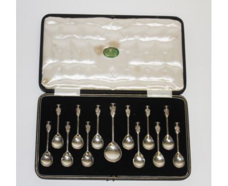 A GOOD SET OF TWELVE EARLY TWENTIETH CENTURY SEAL TOP APOSTLE SPOONS, each with pear-shaped bowl; together with a larger cadd