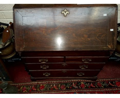 A GEORGIAN SLOPE-FRONT OAK BOOKCASE, the interior fitted with various pigeon hole compartments, drawers and central cupboard,