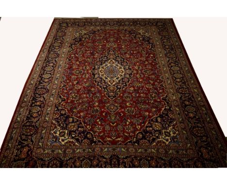 A LARGE FULL-PILE PERSIAN KASHAN CARPET, with centre ivory and dark blue medallion, inside an all-over floral pattern, on bur