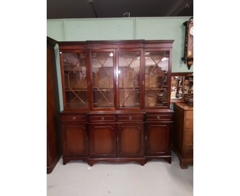 A SMALL GEORGIAN STYLE MAHOGANY BREAKFRONT BOOKCASE, O.R.M., the dentil-moulded cornice above four astragal glazed doors, on 