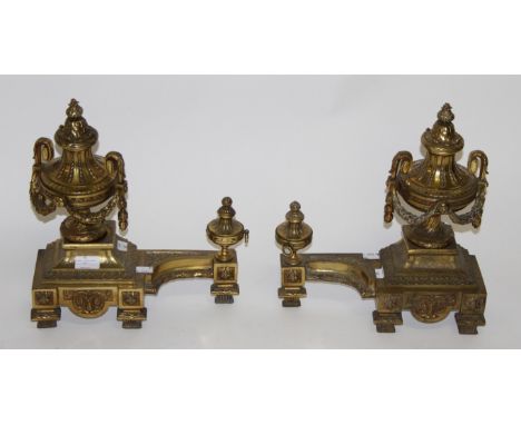 A PAIR OF FRENCH GILT BRASS CHENETS, each in the form of an urn, draped with leaf swags, and a smaller matching urn with ring