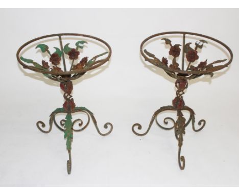 A PAIR OF DECORATED WROUGHT IRON GARDEN OR PATIO TABLES, each with floral decoration, and raised on a leaf moulded tripod bas