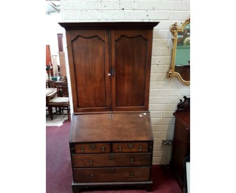 A GEORGIAN OAK BUREAU CABINET, the moulded top over two solid panel doors enclosing adjustable shelves, the base with a slope