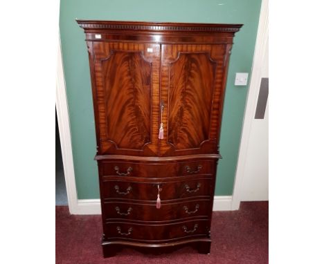 A GEORGE III STYLE SERPENTINE-FRONTED MAHOGANY COCKTAIL CABINET, with dentil-moulded cornice, above two panel doors, enclosin