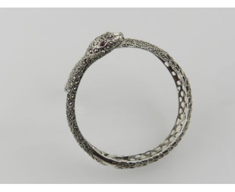 A white metal and marcasite bangle, in the form of a snake, with ruby eyes, stamped 925.