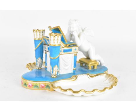 A 19th century Continental porcelain inkwell and pen holder, modelled as a kneeling cherub praying at a lectern, the lectern 