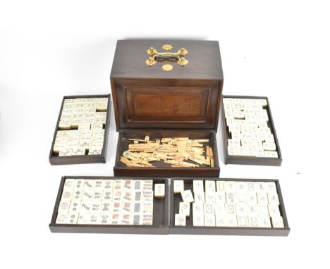 A Chinese Mahjong set, mid 20th century, comprising a set of engraved and inked bone and bamboo tiles, housed in a dark hardw