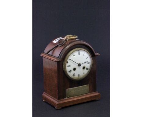 An mahogany cased mantle clock, with a white enamel dial and Roman numerals 