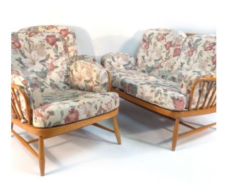 An Ercol beech two seater sofa with a spindle back and loose cushions, together with a pair of matching armchairs   CONDITION