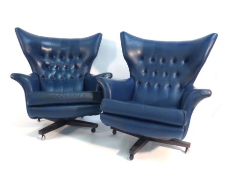 A pair of 1960's G-Plan blue vinyl and button upholstered wingback armchairs on four star bases   CONDITION REPORT:  Cracking