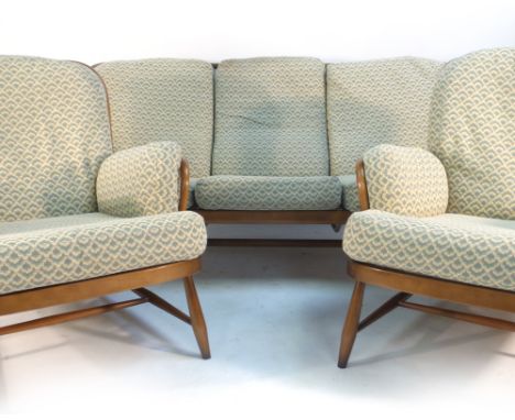 An Ercol stained beech three seater sofa with a spindle back and loose cushions, together with a pair of matching armchairs  