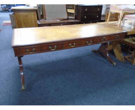 A mahogany three-drawer sofa table with brown leather top with brass-capped feet 