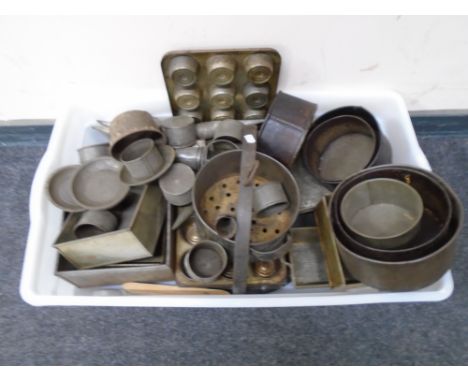 A box containing vintage kitchenalia including muffin dishes, cake tins, press, pipe funnels etc.