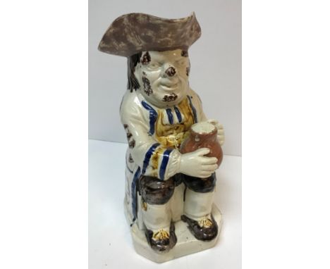 A 19th Century Staffordshire pottery Toby jug as "Toby Philpott seated with a jug of ale on his left knee, sponge decorated w