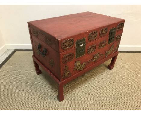 A Chinese red lacquered coffer on associated stand, the front with gilt medallion decoration, raised on scroll supports, 84 c
