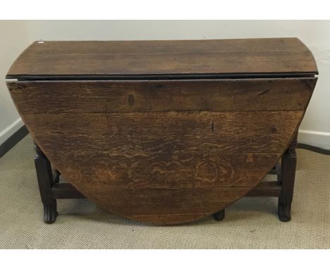 An 18th Century oak oval gate-leg drop-leaf dining table on turned and block supports to splayed feet, with single end drawer