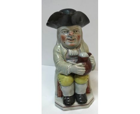A 19th Century Staffordshire pottery Toby jug as "Toby Philpott with jug of ale on his left knee, a pipe in his right hand wi