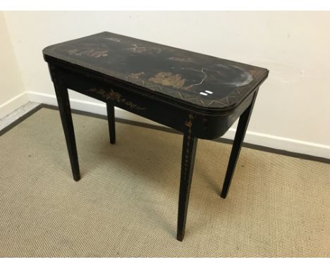 A 19th Century black lacquered and chinoiserie decorated fold-over card table, the top decorated with figures in a waterside 