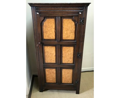 A mid 20th Century oak hall cupboard, the door with six burr walnut veneered fielded panels, opening to reveal a hanging spac